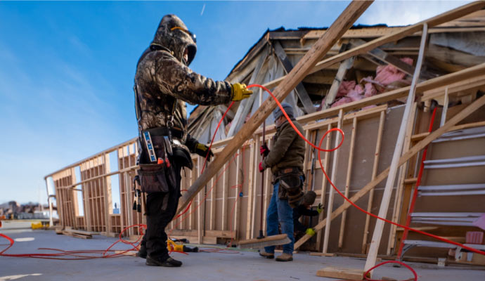 Two individuals are working on a house reconstruction